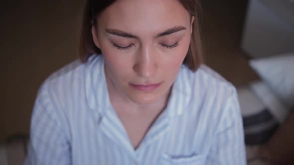 Close-up of a face with closed eyes of a meditating girl in a striped pejama.