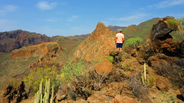 Adventurous Man Hiker Standing on Top of Mountain with Rocky Cliffs