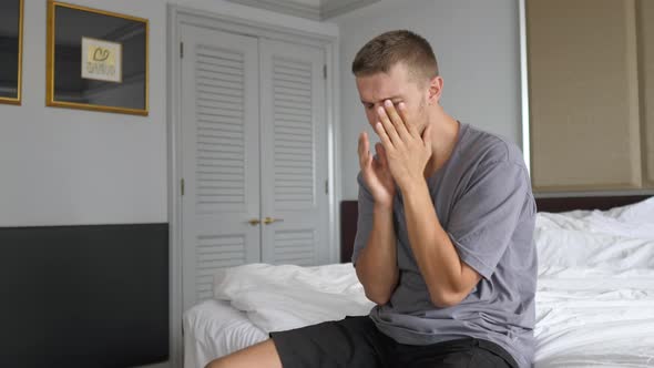 Young Man Struggling Isolated From Human Contact Crying Depressed on His Bed in a Hotel Room