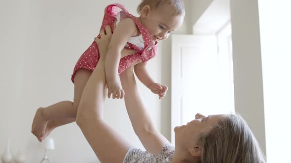 Caucasian Mother Lifting Cute Daughter Over Head