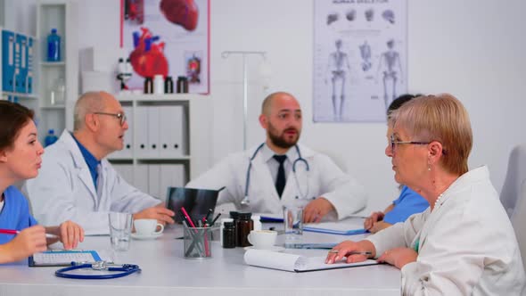 Medical People on Staff Meeting Sitting in Front of Each Other Talking