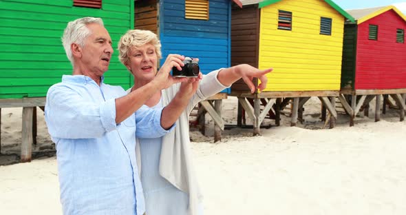 Senior couple clicking photo on camera at the beach