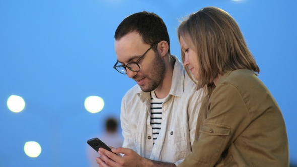 Smart boy showing something on his phone to his girlfriend