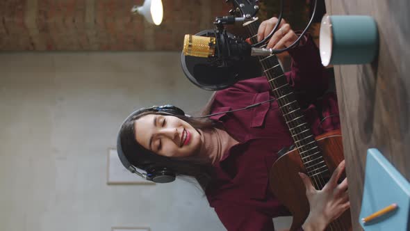 Female Vlogger Playing Guitar and Speaking on Camera in Studio