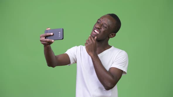 Young African Man Taking Selfie Against Green Background