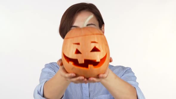 Woman Hiding Her Face Behind Carved Halloween Pumpkin