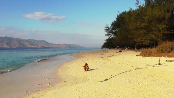 Tourist angler on marine seashore beach break by shallow ocean with white sand background of Gili Ai
