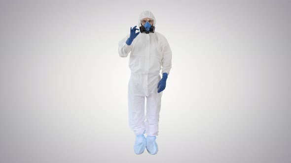 Doctor Wearing Protective Hazard Suit Showing Ok Sign and Thumb Up To Camera on Gradient Background