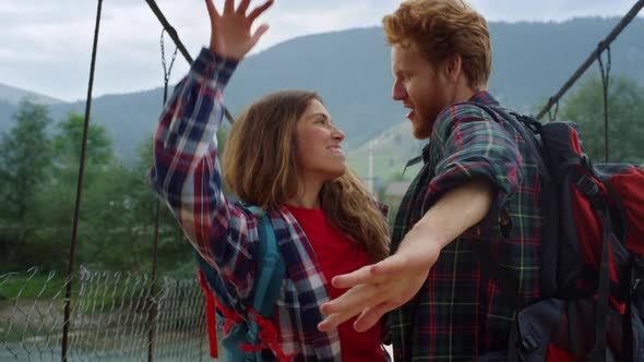 Two Travelers Dance Together on River Bridge