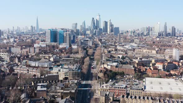 Dolly back drone shot of city of London skyscraper cluster over Whitechapel road