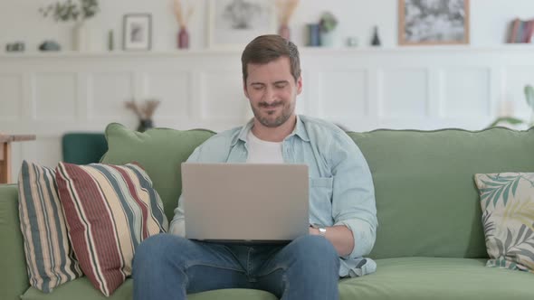 Young Man with Laptop Feeling Angry on Sofa