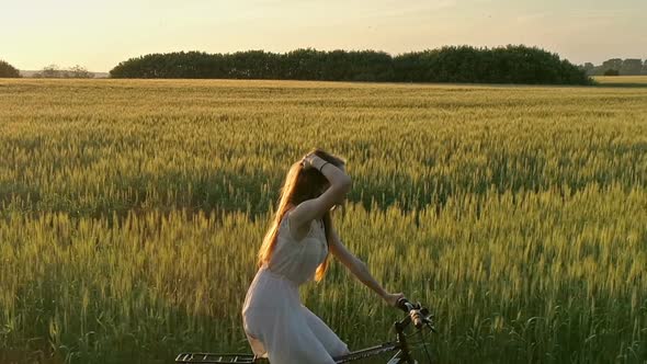 Girl on Bicycle in Green Field Drone Shooting