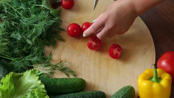 Closeup of a Woman Chef Cuts a Ripe Tomato on a Wooden Chopping Board