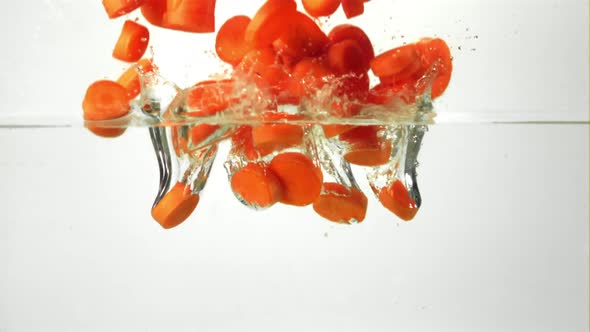 Super Slow Motion Sliced Carrots Fall Into the Water with Splashes and Air Bubbles
