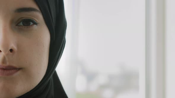 Close Up Half Female Face of Muslim Woman in Black Hijab Indoors