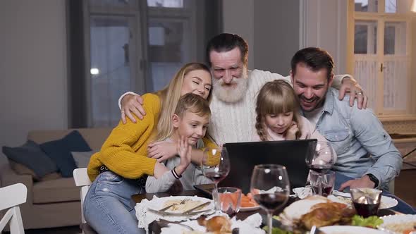 Family Having Video Chat on Computer During Festive Dinner