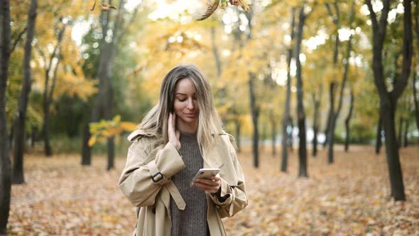 Young Beauty Woman Writing Message on Cell Phone in a Autumn Park