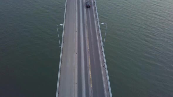 Aerial tilt, top down view of Cars going over massive grand bridge in seascape