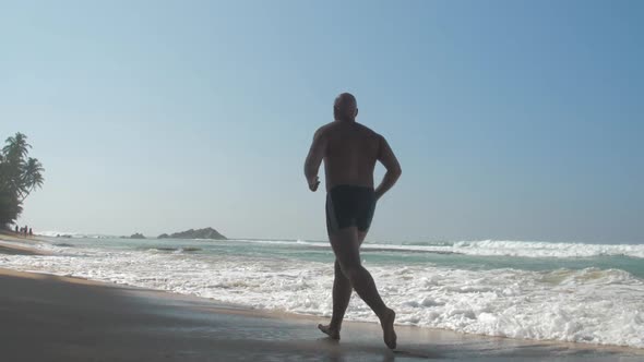 Man Enjoys Jogging Along Abandoned Beach Splashing Waves