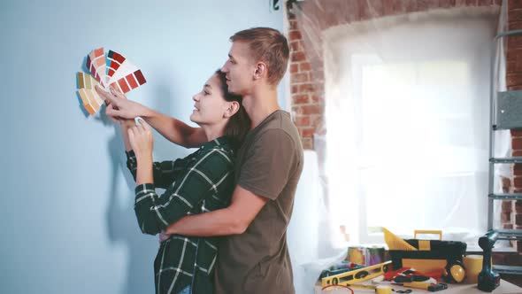 Young Couple Choosing Paint Color From Samples for New Home Interior Design