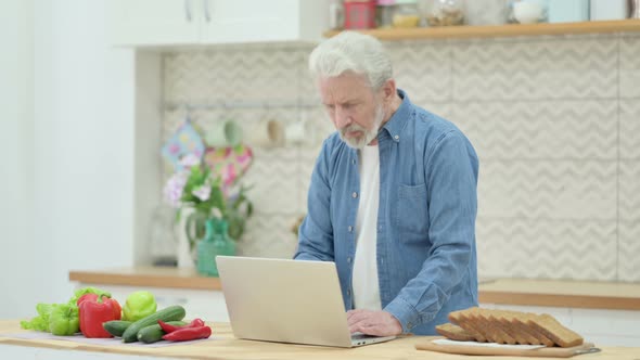 Old Couple Working on Laptop in Kitchen