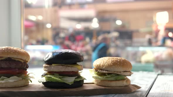 Three Burgers on Wooden Board.