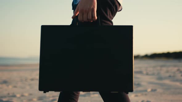 Businessman with Black Briefcase Walks in the Beach Near the Sea