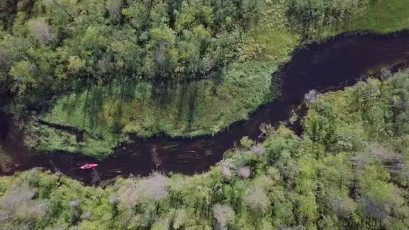 Aerial footage of a male in a red kayak paddling through a river in Lapland with beautiful views.