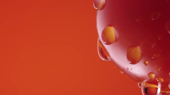 Ripe Tomato in Drops of Water on Red Studio Background