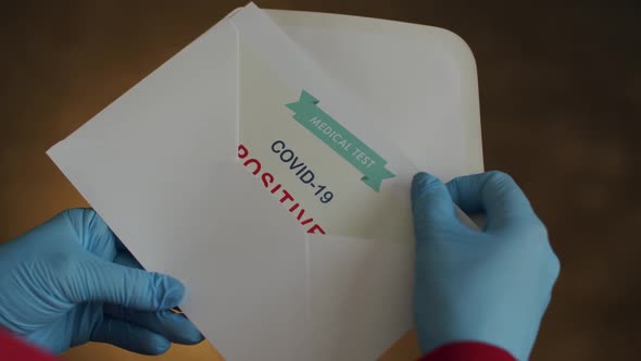 Person Opening Envelope with Certificate with Positive Results in Covid-19