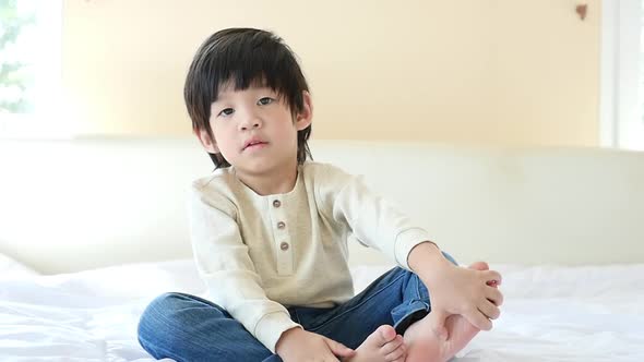 Cute Asian Child Sitting On Bed