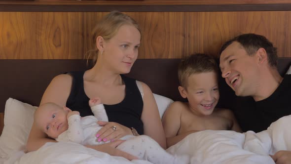 Family of four together in bed at home