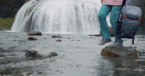 Iceland Woman with Backpack Cross the River in Front of Stjornarfoss Waterfall Near