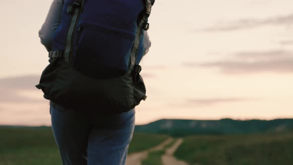 Active Healthy Caucasian Woman with Backpack is Walking Towards a Distant Mountain