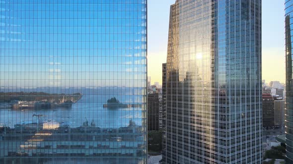 Aerial dolly out of Puerto Madero docks reflected in window glass skyscrapers at sunset, Buenos Aire