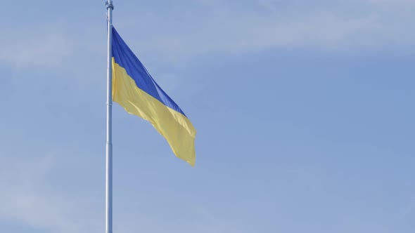Ukrainian National Flag Flutters in the Wind Against the Blue Sky