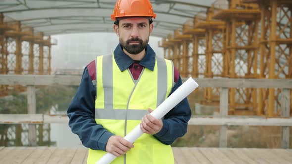 Portrait of Building Professional Standing Outside in Construction Site Holding Blueprint