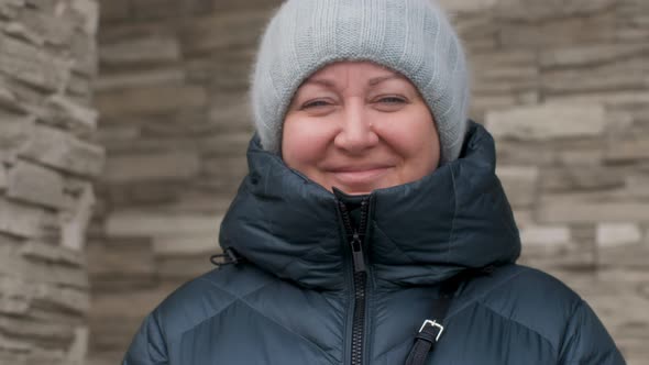 Laughing Chubby Woman in Warm Outerwear and Hat Stand Brick Stone Wall Background  Say Something