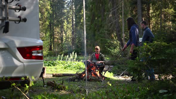 Friends Hanging Out Around Campfire Next to Their Motorhome RV