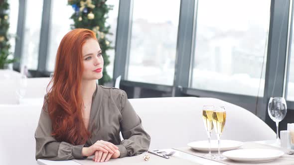 Attractive Red-haired Girl Waits for Her Boyfriend in a Luxury Restaurant in Winter