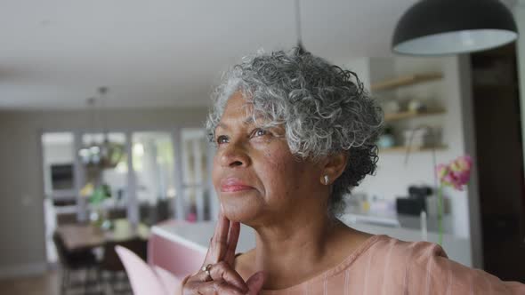 Animation of thoughtful african american senior woman standing in kitchen