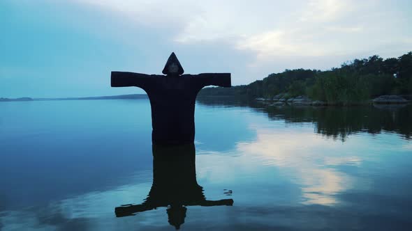 Evil witch in black cloak with hood in the river