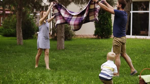 Slow Motion of a Young Family with a Son on a Green Lawn