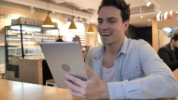 Video Chat on Tablet By Young Man in Cafe