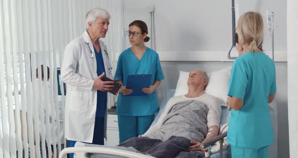 Team of Doctors Examining Elderly Patient Discussing Medical Condition in Hospital Ward