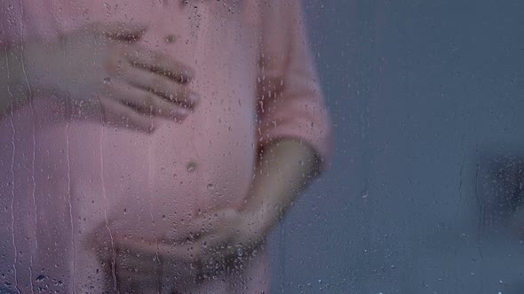 Lonely Pregnant Lady Stroking Big Belly Behind Rainy Window Suffering Depression