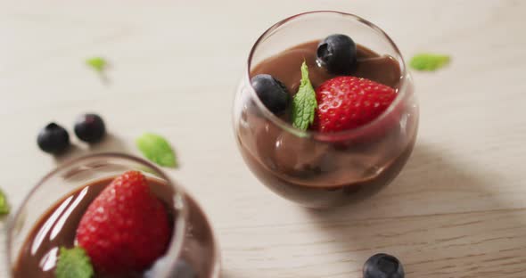 Video of chocolate pudding with strawberries and bluberries on a wooden surface