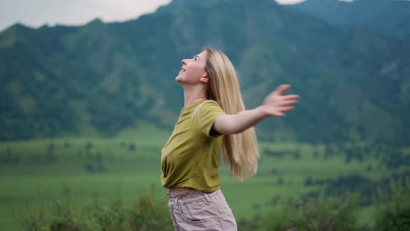 Cheerful Woman Spins Around Over Large Valley Against Hills