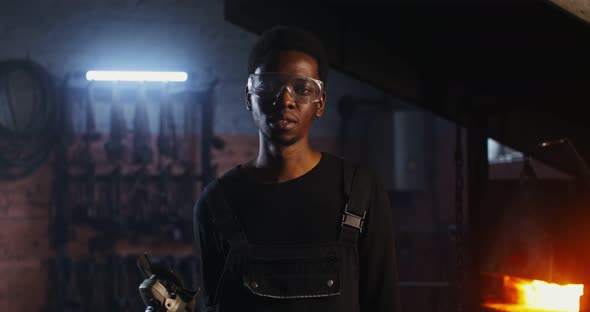 A Young Blacksmith of African American Appearance in Goggles Looks at the Camera