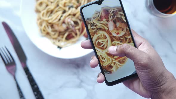 Taking Picture of Plate of Sea Food Pasta with Smart Phone